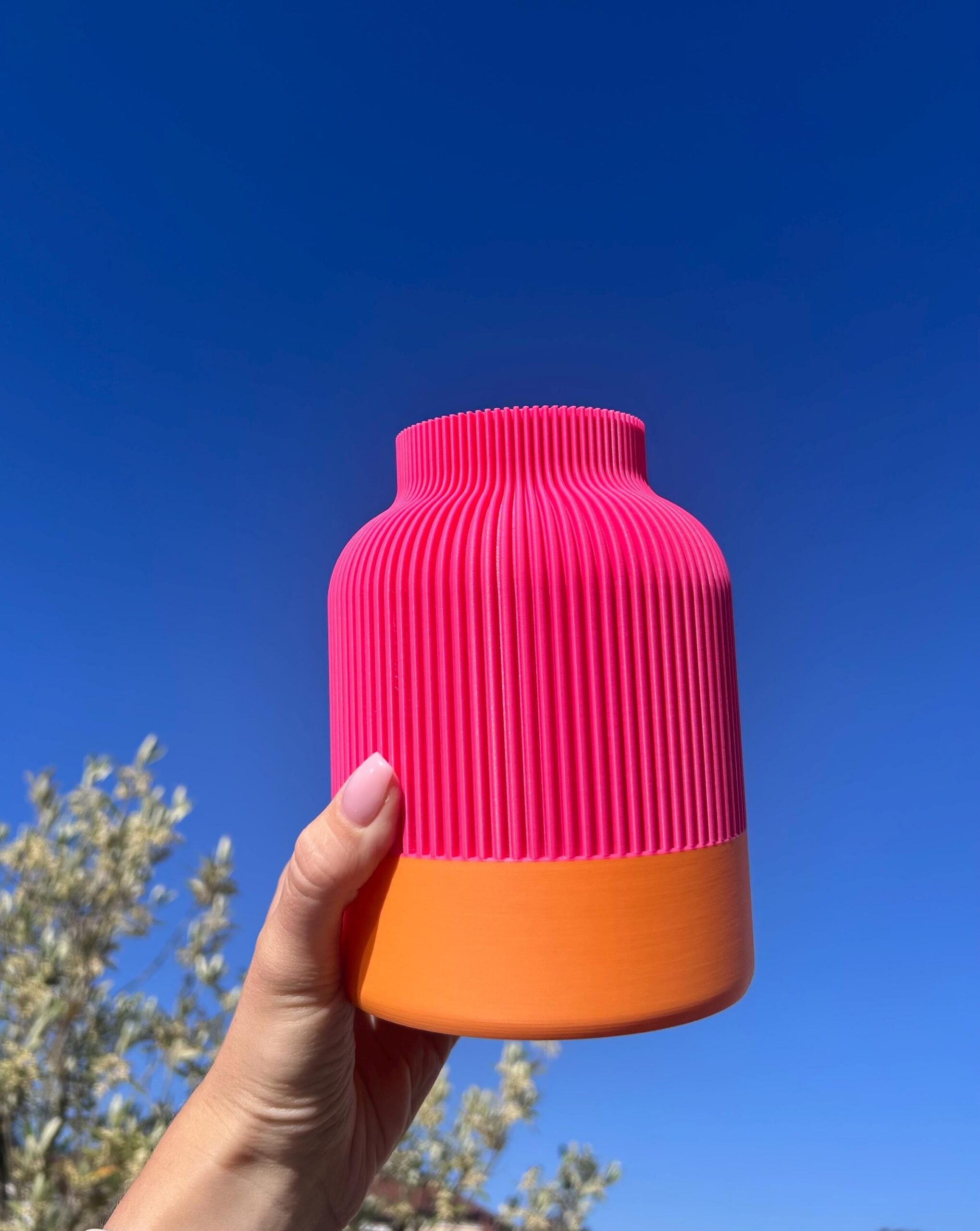 Zweifarbige Vase mit Rillen in Pink und Orange in der Sonne