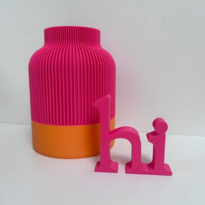 Deko-Set aus geriffelter Vase und 3D-Schriftzug „Hi" in Orange und Heißem Pink auf Sideboard